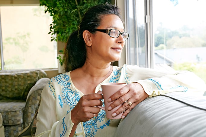 Woman holding tea and looking out the window